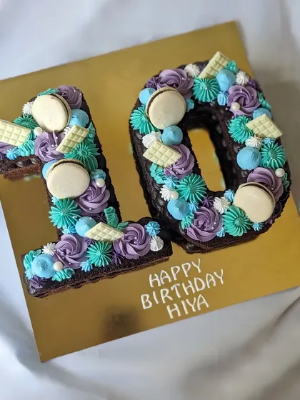A monogram cake for a 10th birthday. This is a brownie cake cut into the shape of the number 10 and decorated with colorful frosting and macarons.