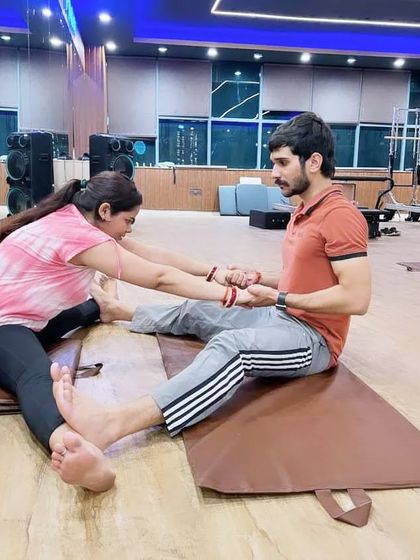 A focused moment of instruction, ensuring the student's form is correct and she feels supported in her stretch.
