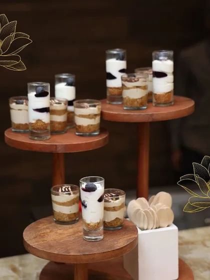 An assortment of dessert parfaits, layered with cake, cream, and fruit, displayed on elegant wooden stands. This offers guests a variety of sweet options to choose from.