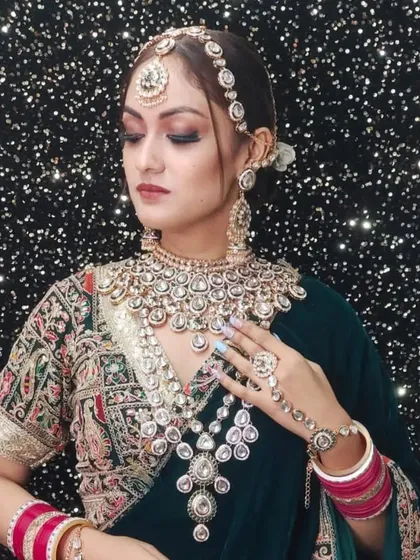 A close-up of a bride wearing a heavy Polki and pearl jewellery set against a dark green velvet blouse. The contrast is absolutely stunning.