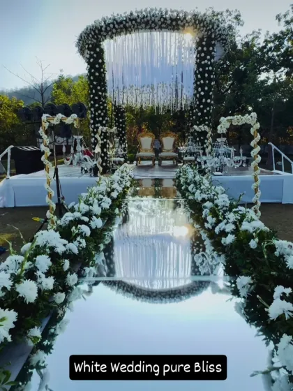 This all-white wedding mandap with a stunning mirrored aisle creates a feeling of pure bliss. It's a perfect example of how we can transform an outdoor lawn into a breathtaking, elegant ceremony space.