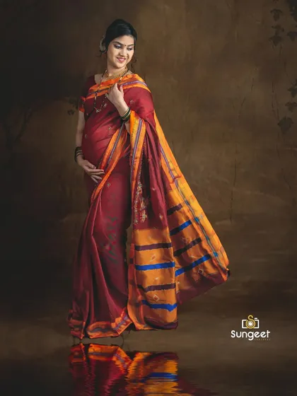 The reflection on the floor adds a creative touch to this portrait, highlighting the vibrant colors of the traditional saree.