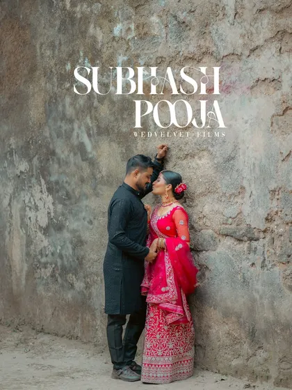 A romantic pre-wedding portrait with a rustic, old-world charm. The weathered wall provides a beautiful texture and backdrop for the couple, who are dressed in elegant traditional attire.