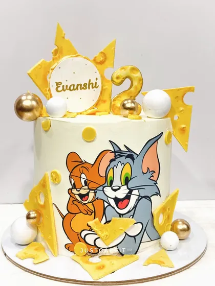 A Tom and Jerry cake with a hand-painted Tom and Jerry and edible cheese accents. The design is playful and perfect for a second birthday.