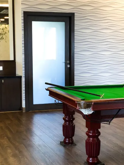 Another view of the games room, showing a textured 3D wave wall panel. This feature adds a modern, sculptural element that contrasts nicely with the classic wooden pool table and flooring.