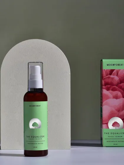 A minimalist product shot of Moon Forest's "The Equalizer" face toner, styled with a simple geometric arch. The clean lines and soft lighting create a modern, serene aesthetic.