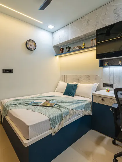 This compact kid's room is designed for maximum efficiency. The bed is flanked by a study desk on one side and overhead cabinets for storage, all in a cool blue and marble-finish theme.