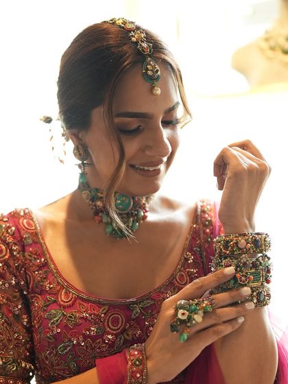A candid of the model during our collaborative shoot. Her smile captures the fun and creative energy on set as she tries on a beautiful fuchsia lehenga and layered gemstone jewelry.