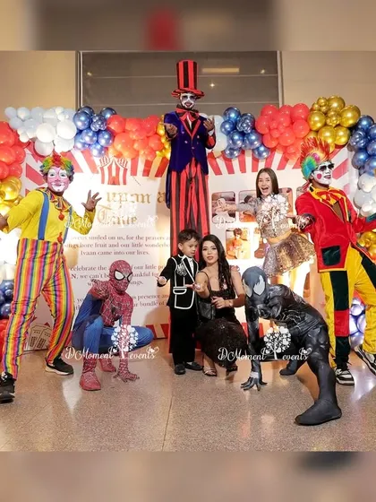 A fun group photo from a carnival-themed party, featuring entertainers like clowns on stilts and Spider-Man characters posing with the birthday boy and his family. This shows my ability to arrange full-party entertainment.