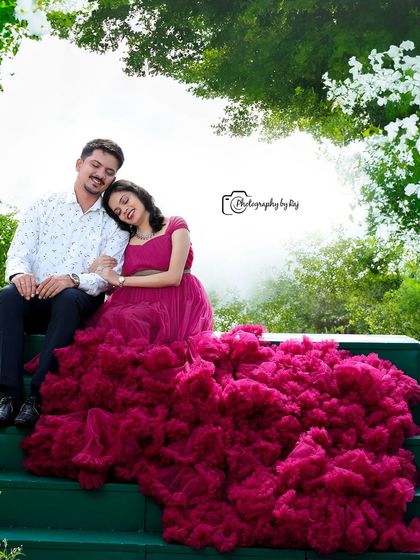 A loving couple's portrait on green steps, with the mother-to-be in a dramatic wine-colored ruffled gown.