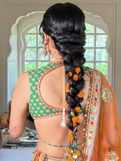 The back view of the loose braid with marigold flowers and a traditional parandi, perfect for a Mehandi ceremony.
