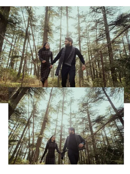 A low-angle shot of a couple walking hand-in-hand through a forest, with the sun filtering through the tall trees, creating a beautiful, cinematic effect.