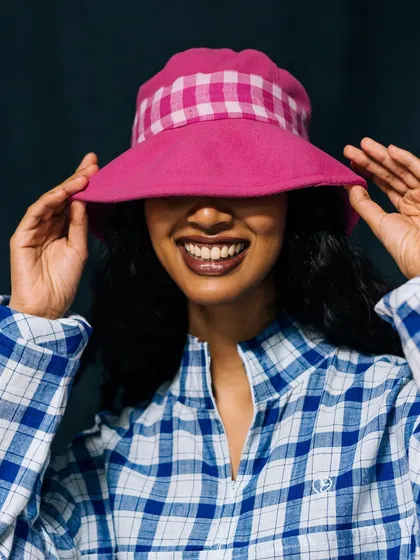 A playful and joyful shot for Label Rama. The model's face is partially hidden by a pink bucket hat, creating a candid and happy moment.