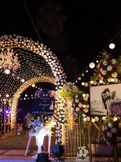A personalized entrance for a reception, featuring a large photo of the couple. The surrounding floral arrangements and the beautifully lit archway make it a warm and welcoming start to the celebration.
