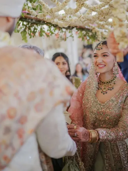 A close-up shot of the bride's happy expression as she sees her groom for the first time. The 'phoolon ki chadar' beautifully frames this emotional moment.