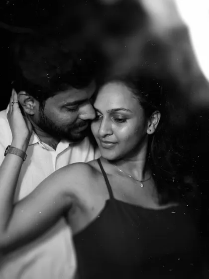 A timeless black and white close-up of a couple in a tender embrace, lit softly in the dark. This artistic portrait focuses on pure emotion and connection, showcasing a classic and intimate style of couple photography.