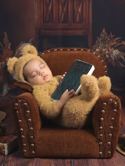 Adding a little story to our teddy bear theme. The baby appears to be "reading" a book while dozing off, a charming and creative touch that adds personality to the portrait.