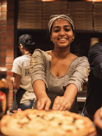 A portrait of one of our happy and talented pizza makers, ready to serve up your next favorite pizza.