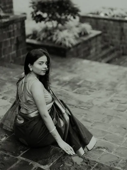An elegant black and white portrait on stone steps. The model's over-the-shoulder glance and the beautiful drape of her saree create a classic and sophisticated composition.