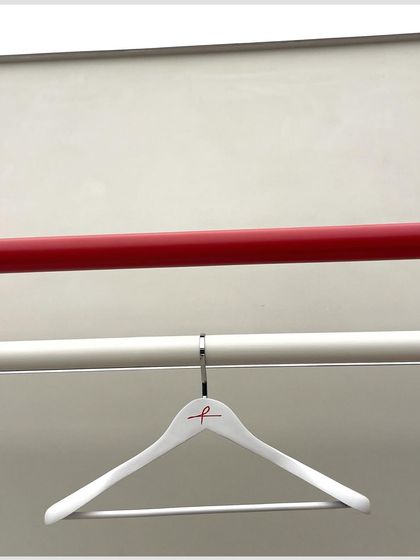 A minimalist shot focusing on the brand's identity, with the custom hanger and the signature red display rod.