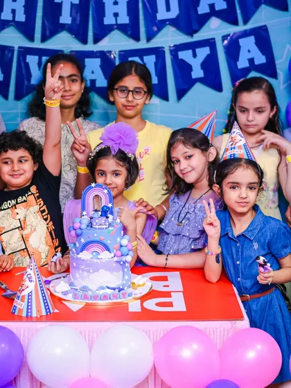 A group of friends posing with the birthday cake. Our party packages ensure all the guests are part of the fun from playtime to party time.