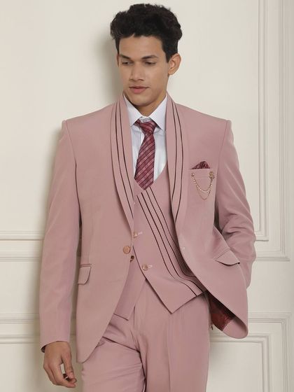 A closer look at the pink suit with lapel detailing and a chain accessory. It’s a modern, stylish take on the classic three-piece suit.