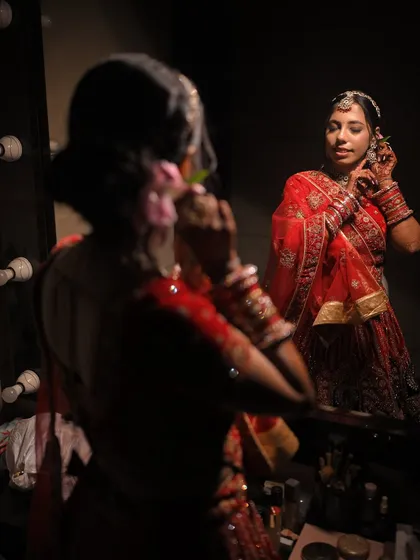 A quiet moment of preparation. This behind-the-scenes shot captures the bride getting ready, her reflection showing the calm and elegance of her final look.