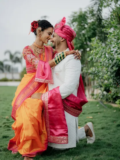 A classic romantic pose with a traditional touch. The groom gets down on one knee, not for a proposal, but in a gesture of love on their wedding day, showcasing their beautiful connection.
