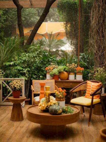A cozy corner at the 'Kesar Sehar' Haldi, surrounded by lush greenery. The design used natural wood furniture and printed textiles to create a warm and inviting atmosphere.
