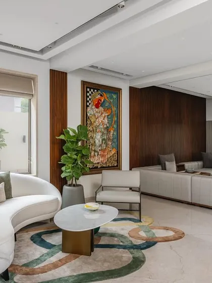 In the living room, a gracefully curved white couch and a mesmerizing, large-scale art piece infuse the space with sophistication. A colorful rug and plush pillows add warmth and personality.