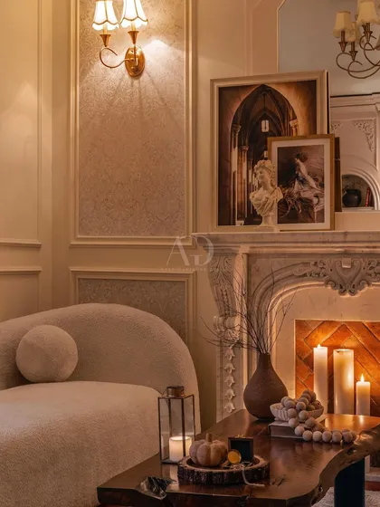 This cozy corner by the fireplace showcases the power of ambient lighting. The warm glow from the candles and wall sconce creates an intimate and inviting atmosphere, perfect for a quiet evening.