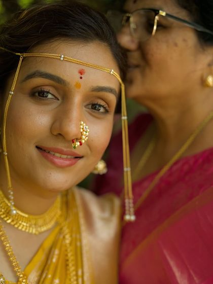 A close-up of a bride and her mother sharing a special moment. The bride's traditional Marathi nath and mundavalya are beautifully highlighted.