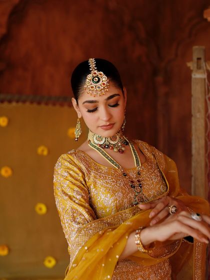 A detailed shot of the traditional jewelry and makeup. The winged eyeliner and defined brows add a touch of regal elegance.