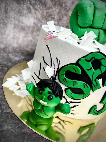 A side view focusing on the mini Hulk fondant figure, showing his determined expression and the "smashed" sugar shards around him.