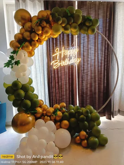 A modern and organic balloon arch on a ring frame for a birthday party. The combination of olive green, white, and chrome gold balloons creates a sophisticated and trendy look.