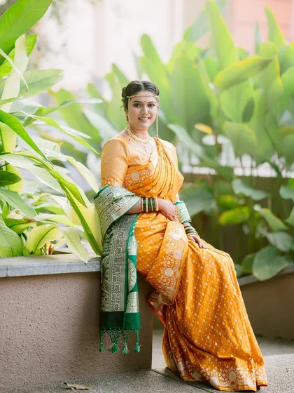 A serene bridal portrait. The bride, Mansi, sits gracefully amidst lush greenery, her yellow saree glowing in the soft light.
