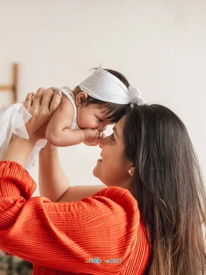 Lifting her baby up for a sweet nose-to-nose moment. These are the playful, loving interactions that make for unforgettable family photos.