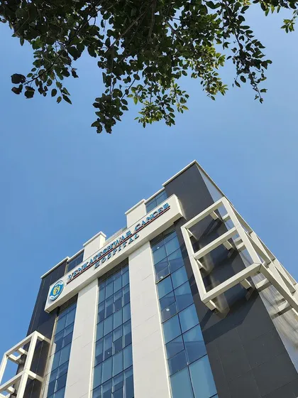 An upward-looking shot of the Venkateshwar Cancer Hospital against a clear blue sky. The design features strong vertical lines and contrasting materials to create a modern and reassuring presence.