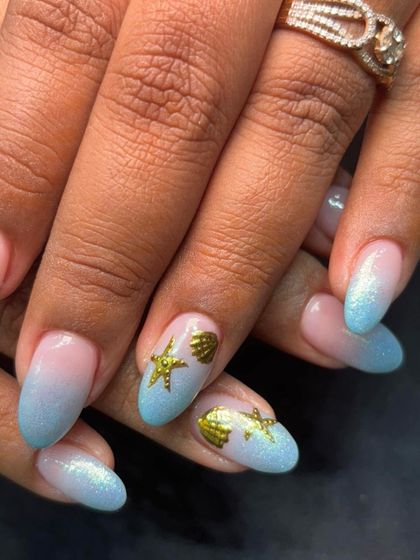 A close-up of the adorable starfish and seashell charms on this ocean-themed manicure.