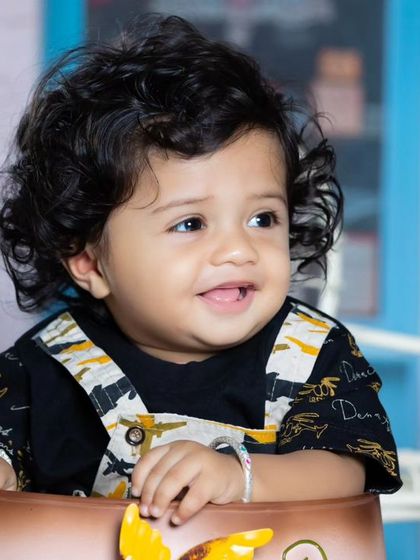 A close-up of the happy baby in the watering can, with a charming smile.