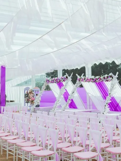 The guest seating arrangement for the carnival, with chairs decorated in alternating pink and white, under a large white tent.
