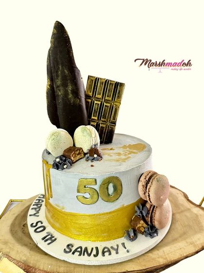 Celebrating a 50th birthday in style. This cake features my signature buttercream, a dramatic dark chocolate sail, and delicate macarons for a modern and sophisticated look.