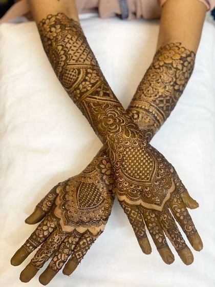 A beautiful crossed-arm pose showing the symmetry and detail in bride Sunera's full bridal henna. The patterns are designed to look beautiful from every angle.