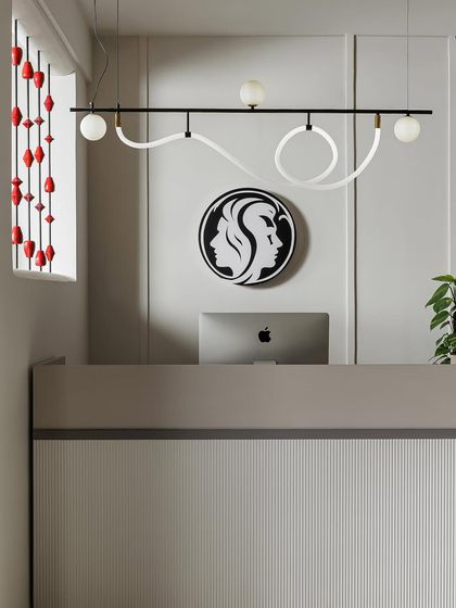 This front view of the reception desk showcases the interplay of textures and forms. The fluted detail on the desk, the sculptural light fixture, and the bold brand logo create a memorable first impression.
