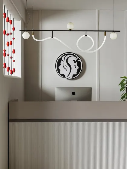 A close-up of the reception desk, featuring a modern, sculptural light fixture that doubles as art. The ribbed texture of the desk front and the clean lines of the logo create a refined and highly branded first impression.