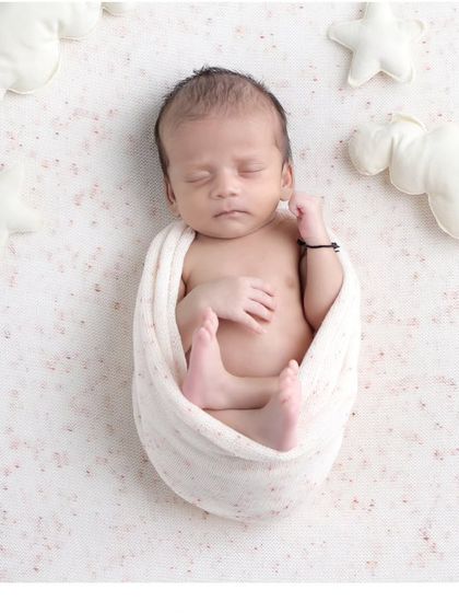 A minimalist celestial theme with the baby swaddled in white, surrounded by soft cloud and star props for a clean and serene look.