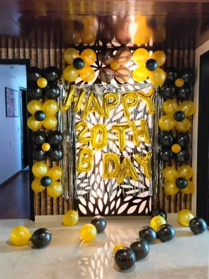 A 20th birthday party with a unique black and yellow balloon flower design. We framed a decorative wall panel with a shimmer curtain and balloon arrangements for a striking look.