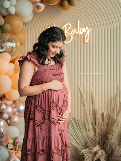 An expectant mother gently holds her baby bump during her baby shower celebration. This portrait, set against a stylish 'Oh Baby' backdrop, highlights the beautiful anticipation and glow of motherhood.