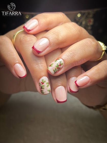 Minimal base, artisanal detail. A chic Christmas design with classic red French tips and accent nails featuring hand-painted holly.