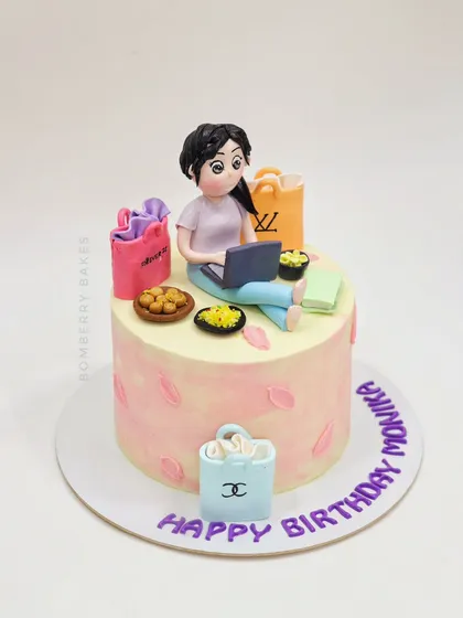 A cake for a shopping lover, topped with a figurine surrounded by luxury shopping bags and snacks.